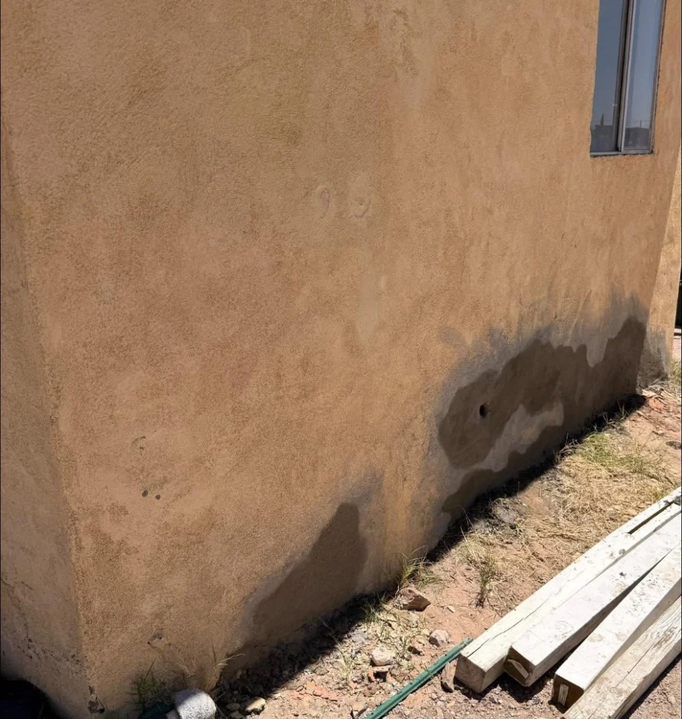 Water staining tracking down a stucco wall near a window base on a Las Cruces home