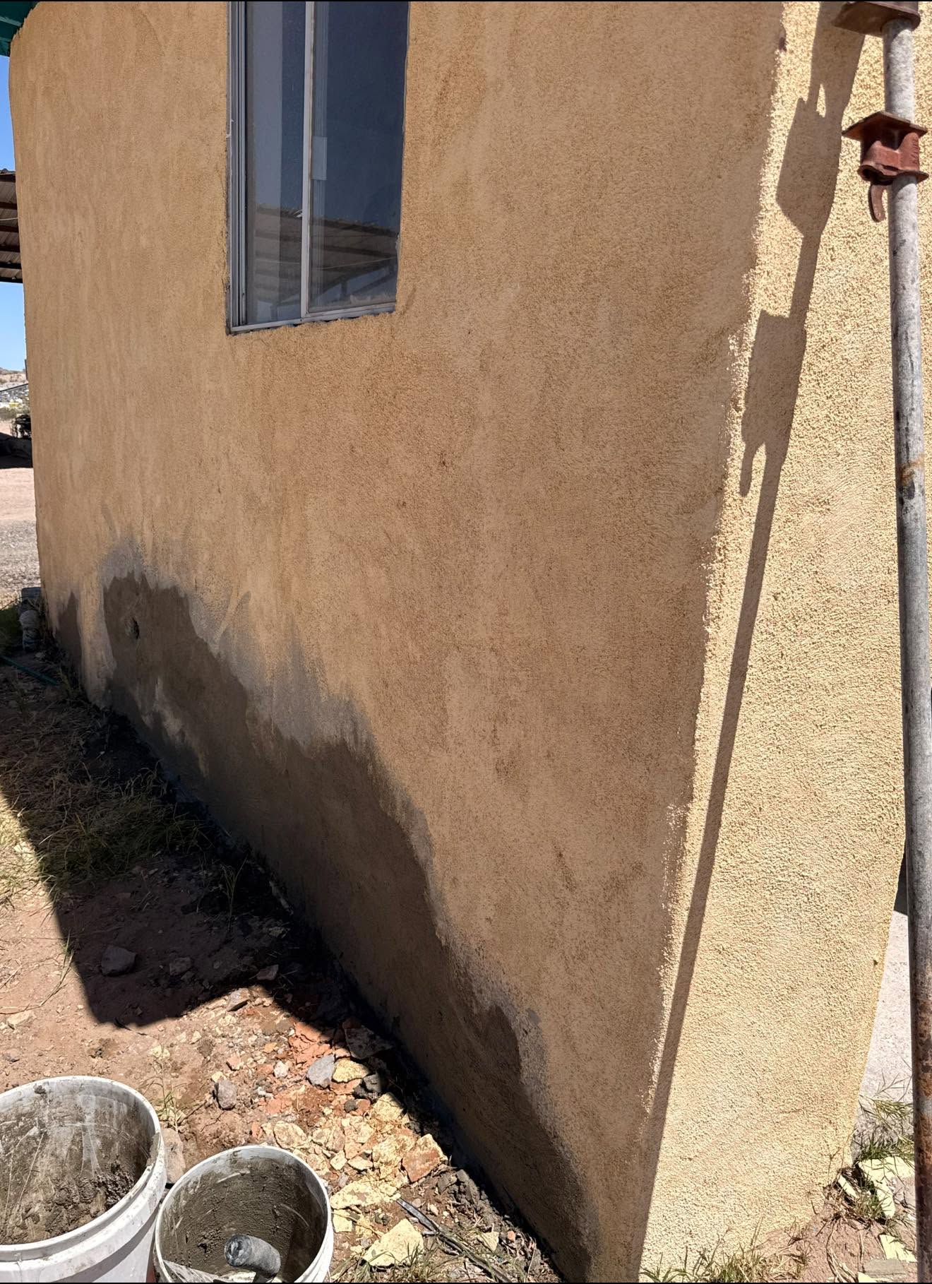 Water staining at the base of a stucco wall in Las Cruces before repair